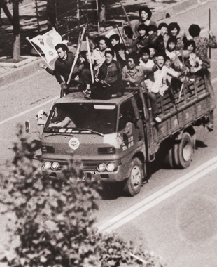 시민군들이 태극기를 휘날리며 시내를 질주하자 시민들이 박수치며 격려하고 있다.